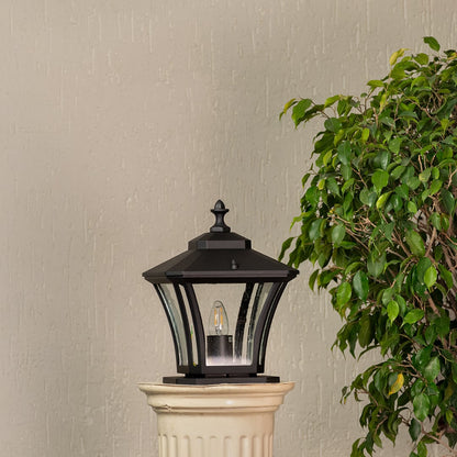 Black pillar lantern crafted in metal with clear textured glass shown unlit for outdoor home entrance styling.