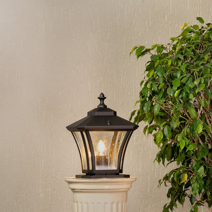 Elegant black metal pillar lantern glowing warmly with clear glass panels for outdoor garden or porch lighting.