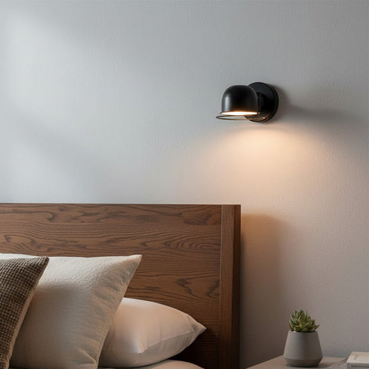 Modern black metal wall light with warm glow for stylish bedroom and contemporary home decor spaces.

