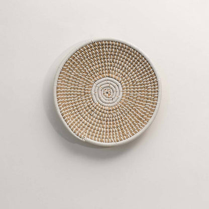 Round handcrafted natural seagrass wall basket with woven pattern for boho décor on white background image.