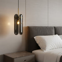 Black metal wall light with warm glow mounted beside bed in contemporary bedroom interior setting.