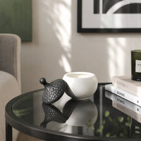 Black textured ceramic storage jar placed on glass table for elegant contemporary home decor styling.