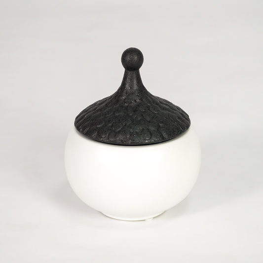 White ceramic storage jar with black lid for stylish kitchen shelf placement and contemporary decor styling accent.