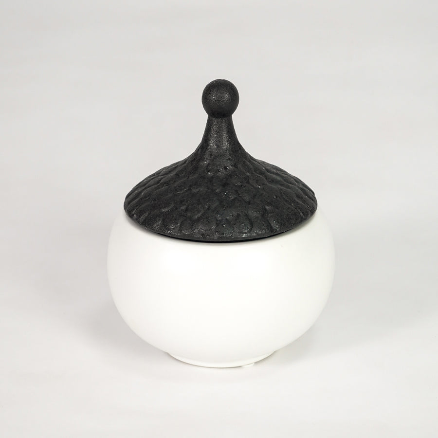 White ceramic storage jar with black lid for stylish kitchen shelf placement and contemporary decor styling accent.