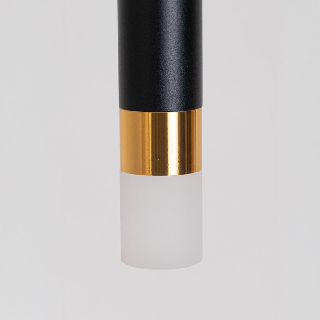Closeup of black and gold cylindrical pendant light with frosted diffuser base showing premium detailing and fine finish.