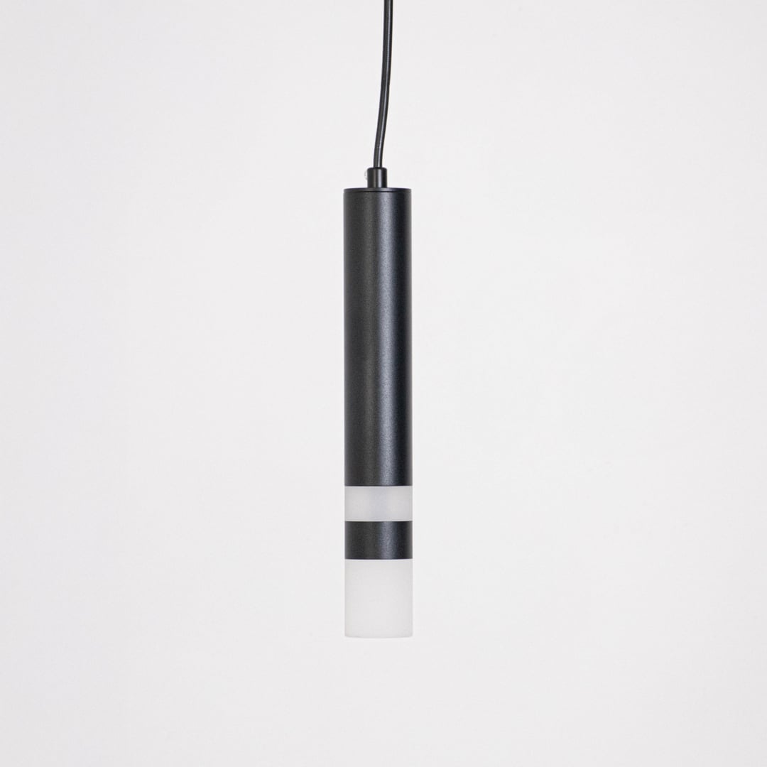 Minimalist black cylindrical pendant light turned off displayed on white background for catalog product showcase.