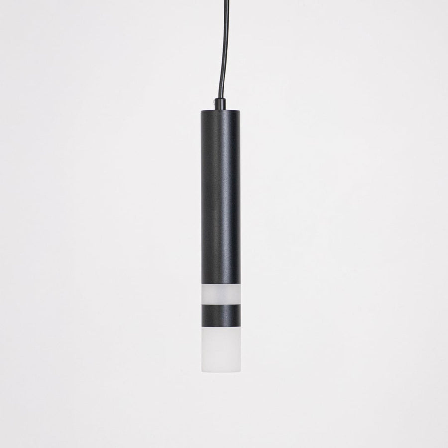 Minimalist black cylindrical pendant light turned off displayed on white background for catalog product showcase.