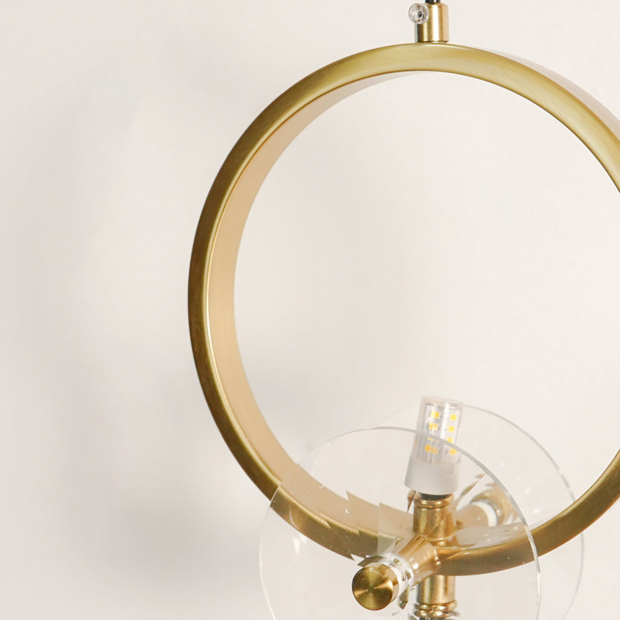 Detailed close up view of a modern gold brass ring wall sconce showcasing the metallic finish and clear glass mount.