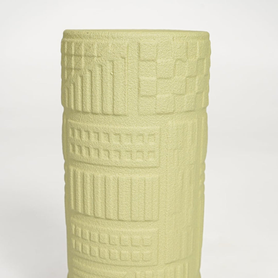 Detailed closeup of yellow ceramic cylindrical vase showcasing carved textured surface and modern design.