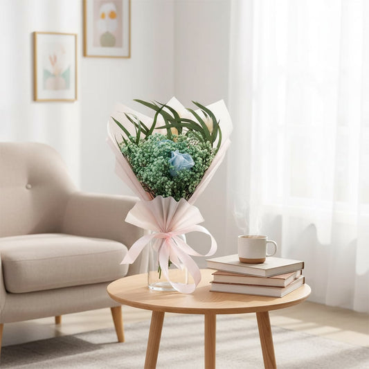 Lifestyle image featuring preserved dried flower bouquet in glass vase styled on wooden coffee table with sofa books and soft daylight creating calm home decor mood.