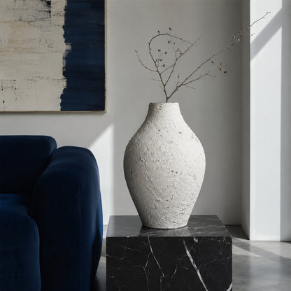 Textured white artisan ceramic vase with branch on black marble table for luxury home decor and modern living room.