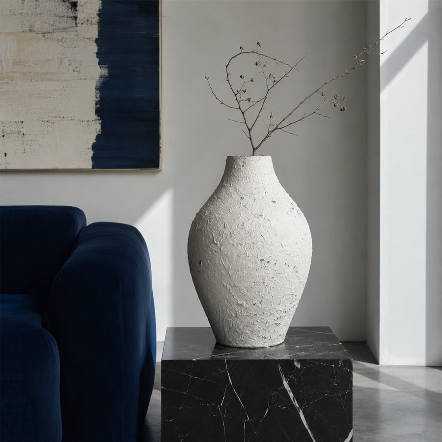 Textured white artisan ceramic vase with branch on black marble table for luxury home decor and modern living room.