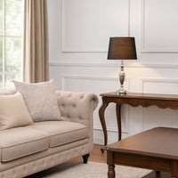 Elegant black table lamp with a polished gold base placed beside a vintage gramophone on a wooden side table.