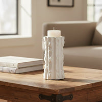 White textured candle holder with white candle placed on wooden table for modern decor styling.