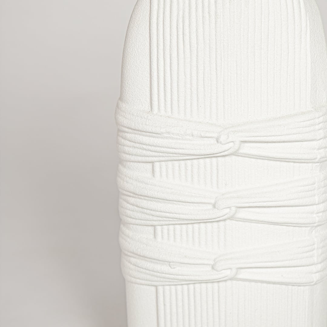 Detailed closeup of white ceramic sculpted vase highlighting vertical ribbed texture and refined matte finish.