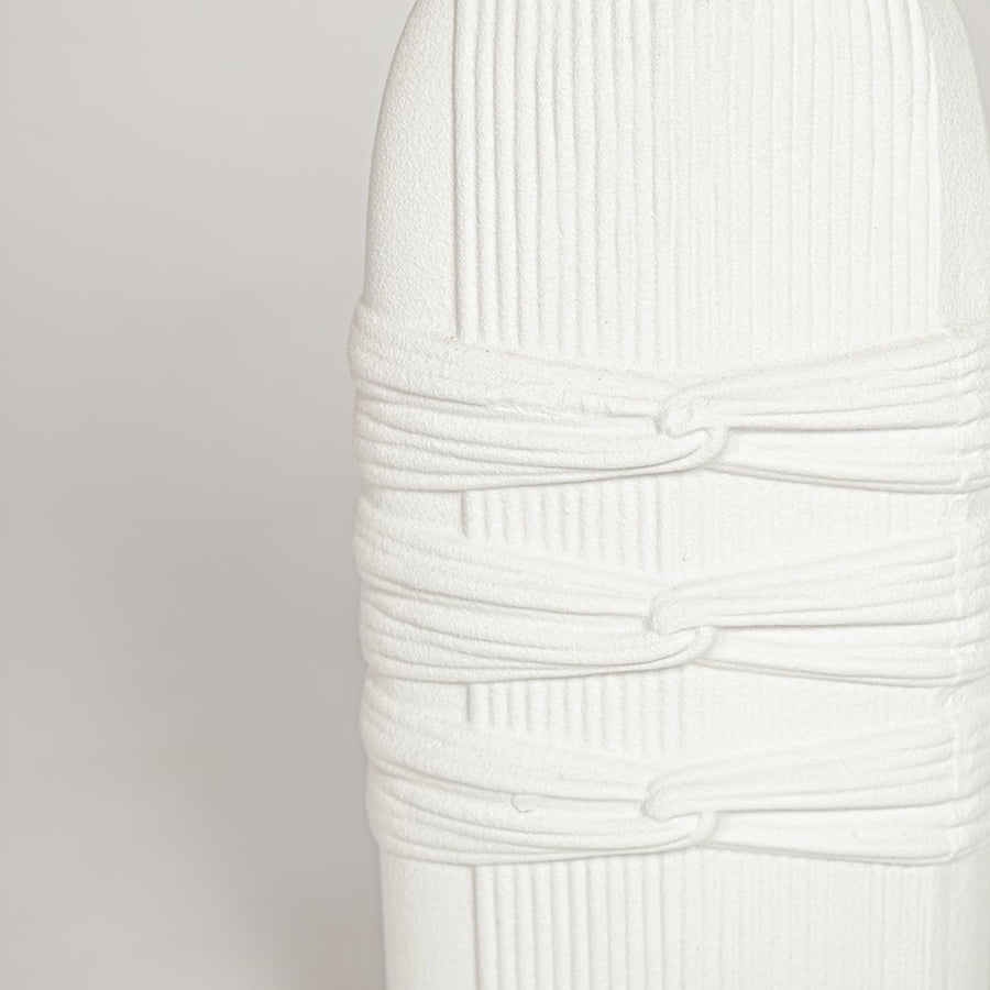 Detailed closeup of white ceramic sculpted vase highlighting vertical ribbed texture and refined matte finish.