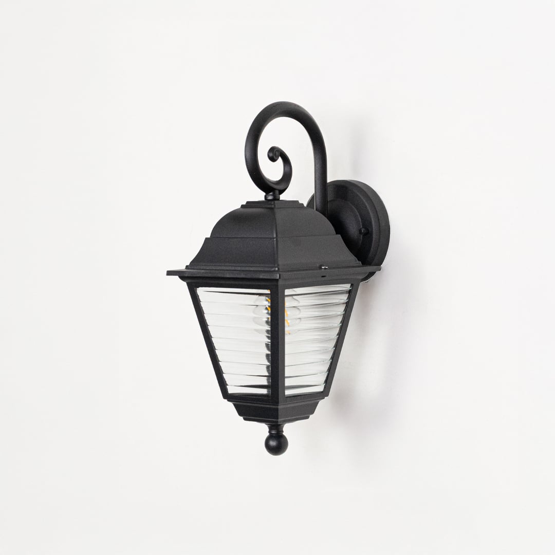 Outdoor wall lantern in black metal switched off on white background highlighting ribbed glass texture and classic form.