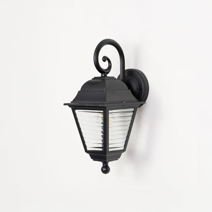 Outdoor wall lantern in black metal switched off on white background highlighting ribbed glass texture and classic form.