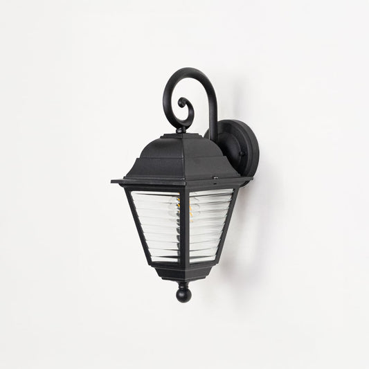 Outdoor wall lantern in black metal switched off on white background highlighting ribbed glass texture and classic form.