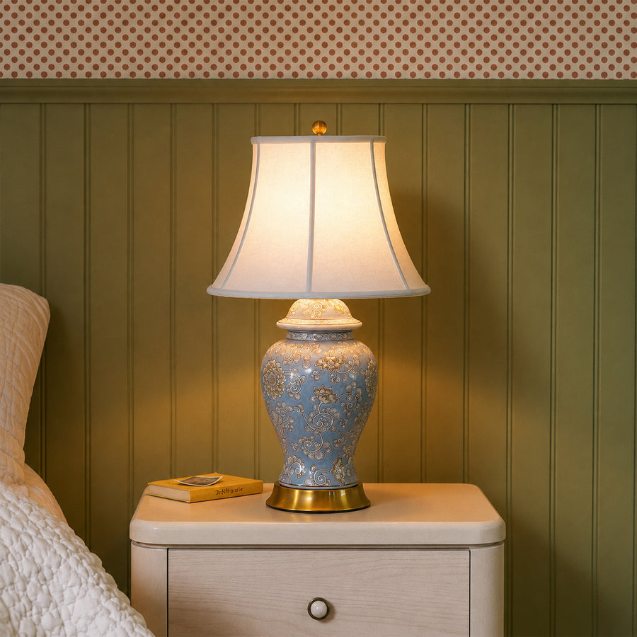 Blue floral ceramic table lamp with fabric shade placed on a bedside table creating cozy traditional bedroom lighting.