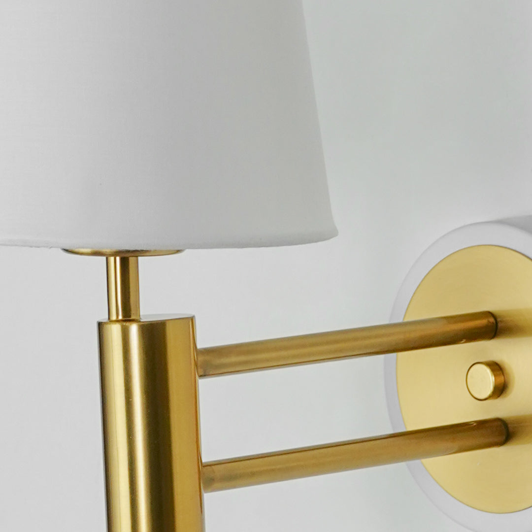 Closeup image of gold metal wall light with white fabric shade for stylish luxury interior wall decor.