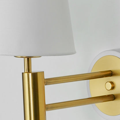 Closeup image of gold metal wall light with white fabric shade for stylish luxury interior wall decor.