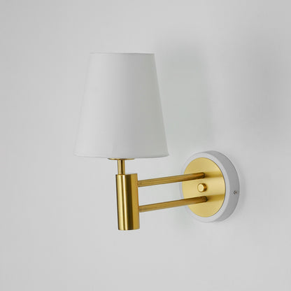 Gold metal wall light on white background with fabric shade for elegant modern bedroom wall decor.