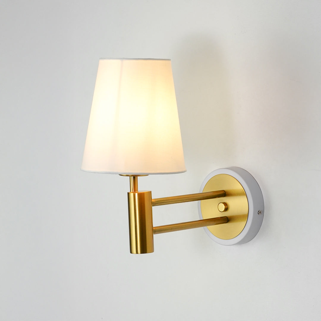 Gold metal wall light on white background with fabric shade for elegant modern interior wall decor.