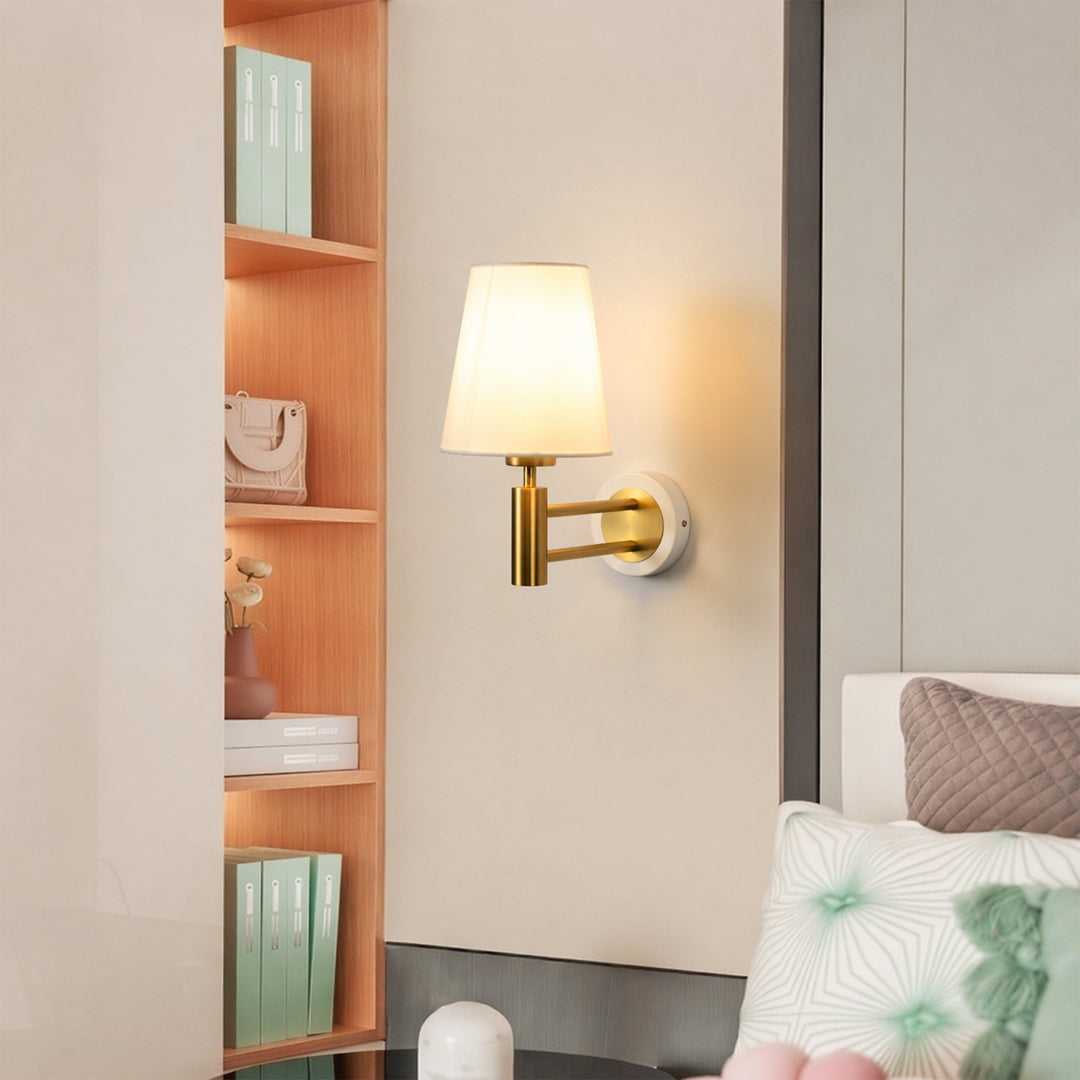 Gold metal wall light lifestyle image with fabric shade for cozy modern bedroom wall lighting decor.