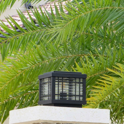 Black outdoor gate light styled beside tropical plants for modern garden and exterior decor ambiance.