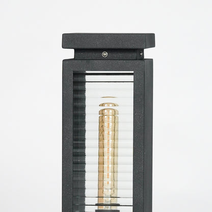 Closeup of black metal outdoor bollard light with clear glass panels for elegant exterior lighting decor styling.