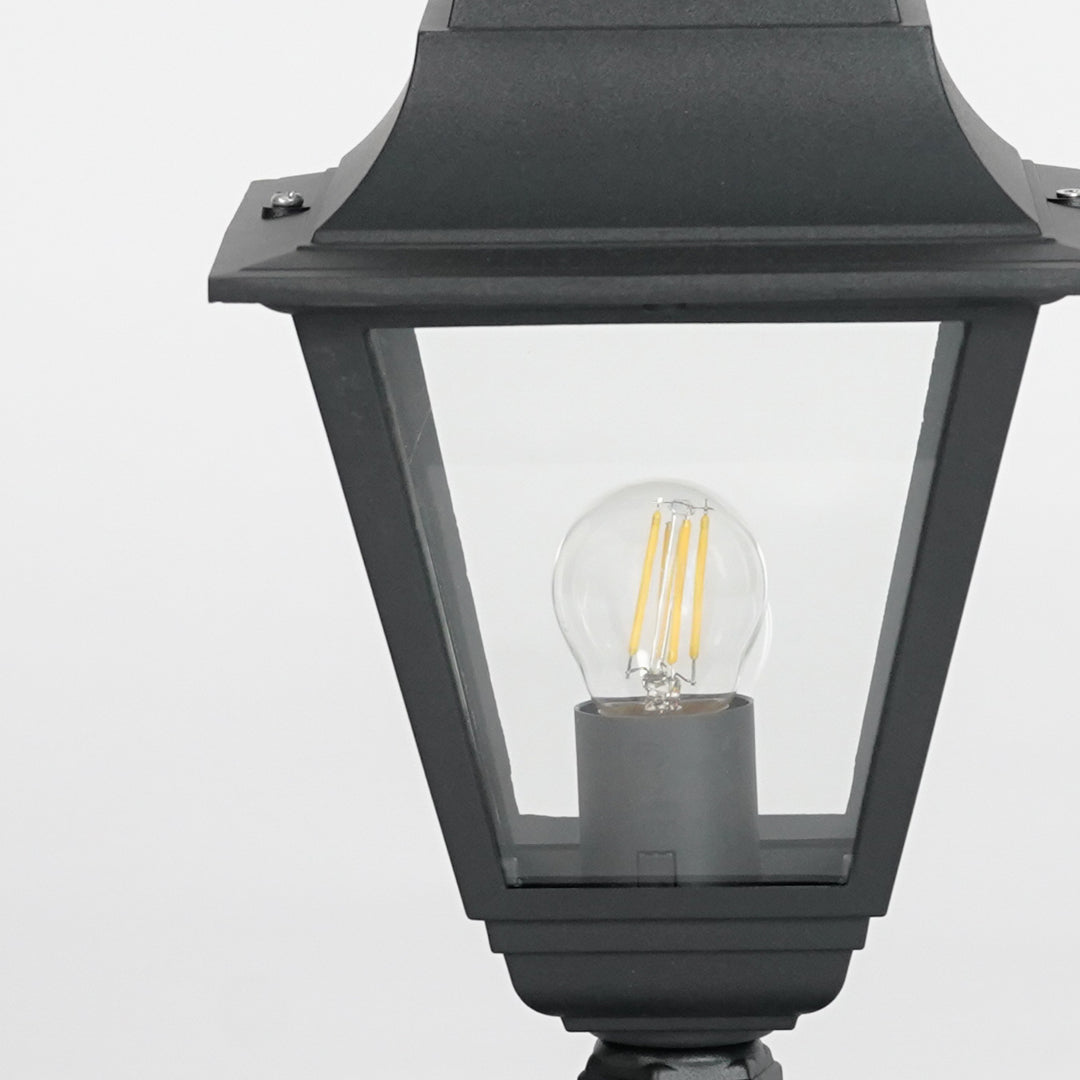 Closeup of black metal outdoor gate light with glowing bulb for elegant exterior decor styling use.