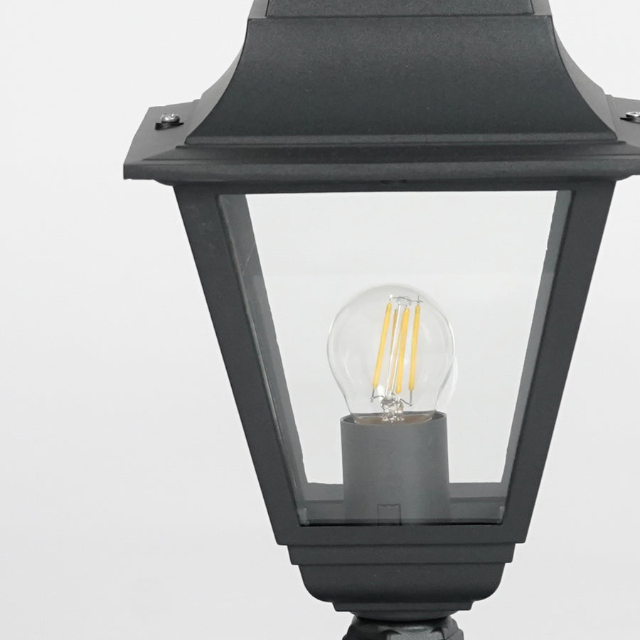 Closeup of black metal outdoor gate light with glowing bulb for elegant exterior decor styling use.