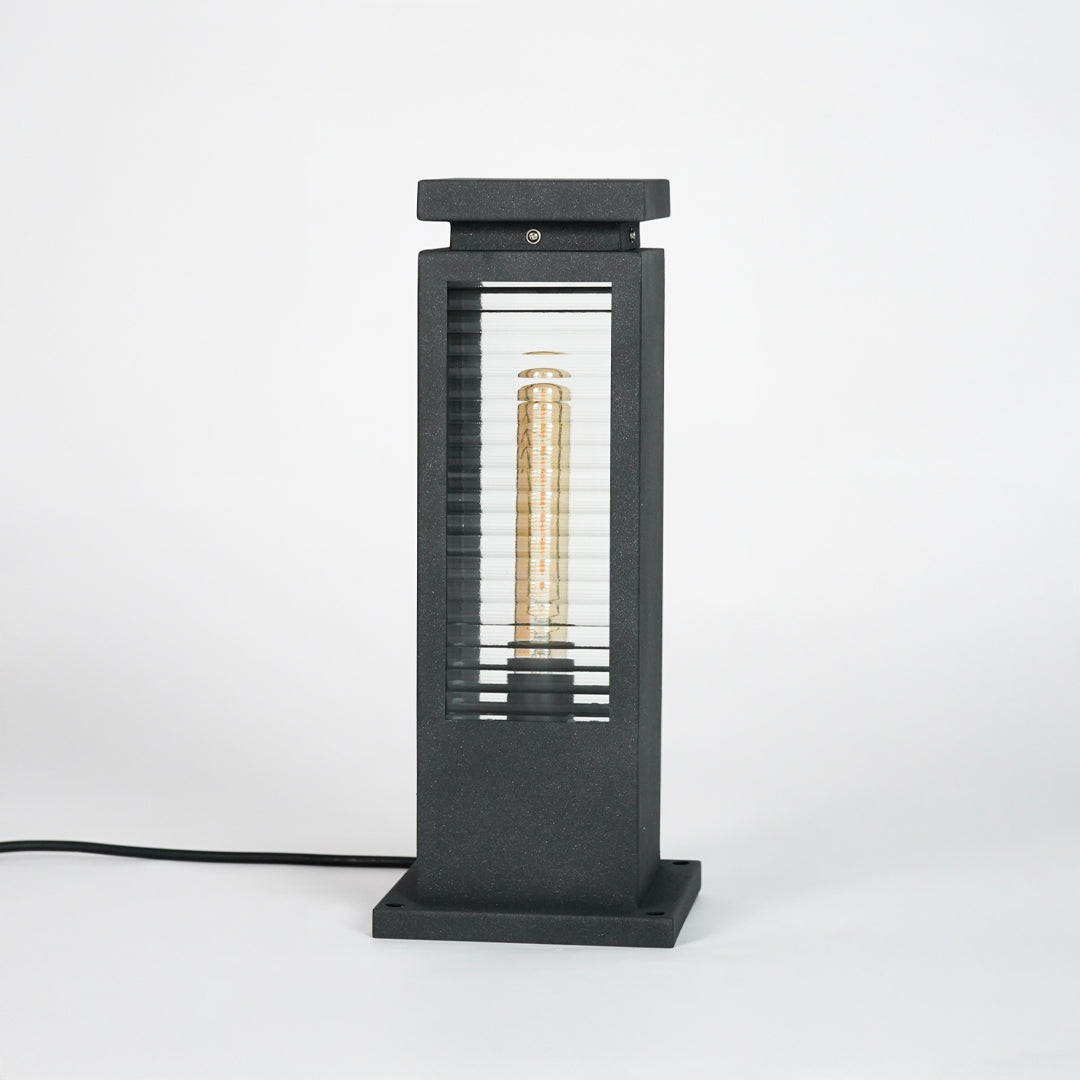 Black metal outdoor pathway light with glass enclosure for modern garden and exterior lighting decor placement.
