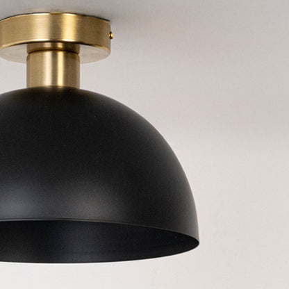 Closeup of black ceiling light with gold base and dome shade for elegant modern ceiling lighting and home interior decor.