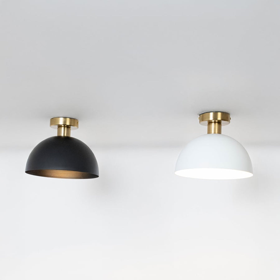 Black and white ceiling lights with gold fittings and dome shades glowing on white background for modern home lighting.