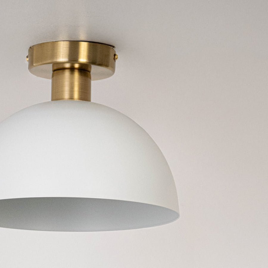 Closeup of white ceiling light with gold base and dome shade for modern ceiling lighting and elegant home interior decor.