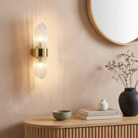 Luxury gold brass fluted glass wall sconce lamp glowing beautifully in a contemporary living room for warm ambient lighting.