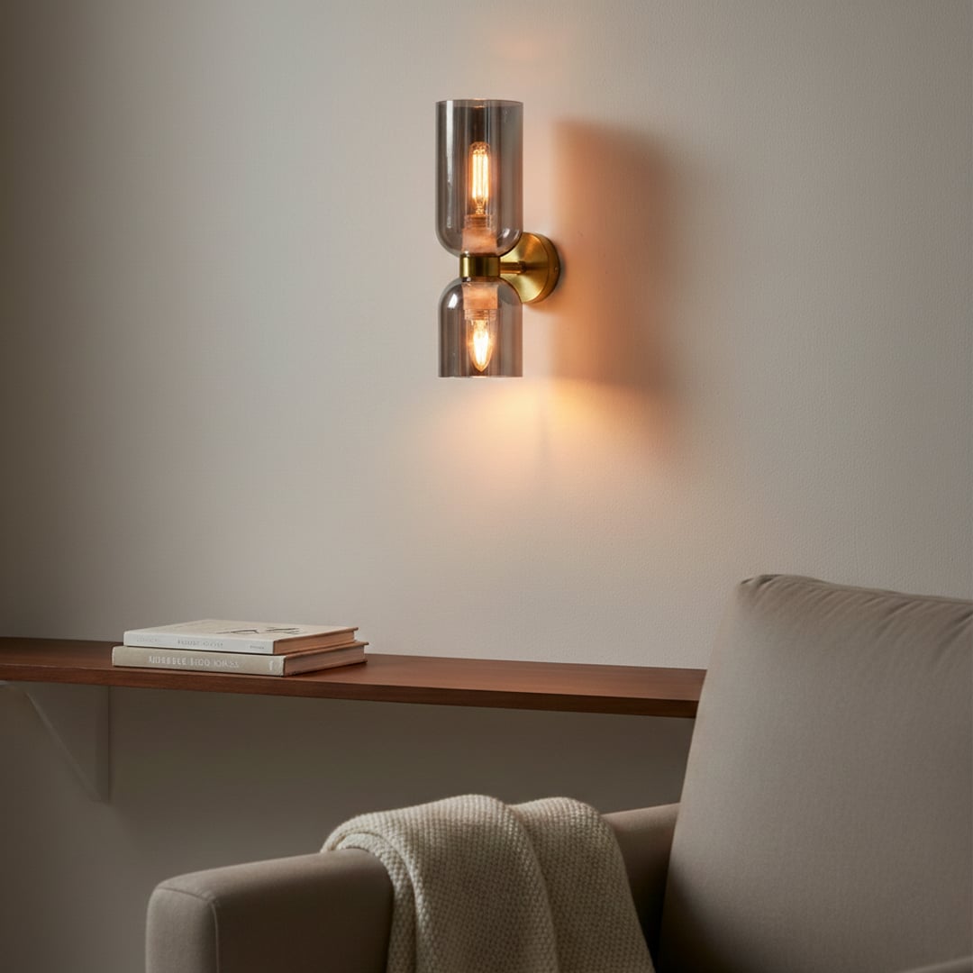 Modern gold metal wall light with dual smoked glass shades mounted in luxury living room setting.