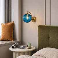 Lifestyle image of modern globe brass wall light in blue for elegant hallway decor styling and modern home room lighting.
