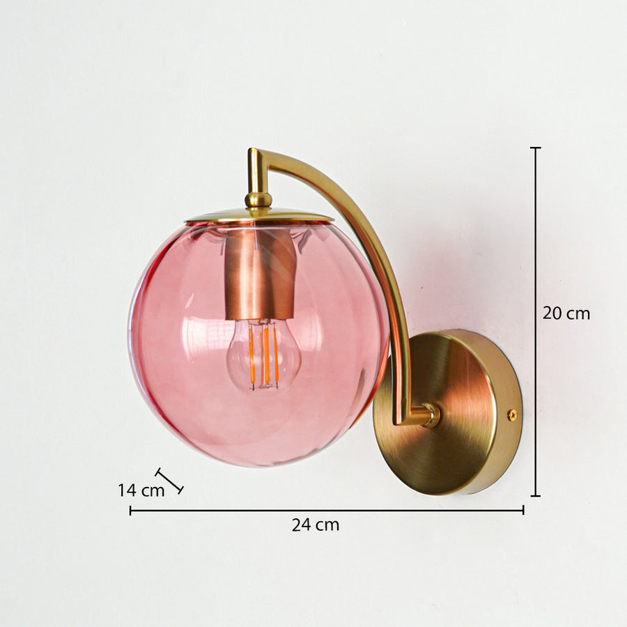 Stylish pink glass wall light with gold metal mount displayed against clean white background suitable for modern bedroom or living space lighting.