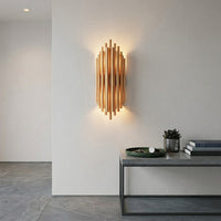 Luxury rose gold copper metal vertical tube wall sconce illuminated brightly in a minimalist hallway entrance setup.