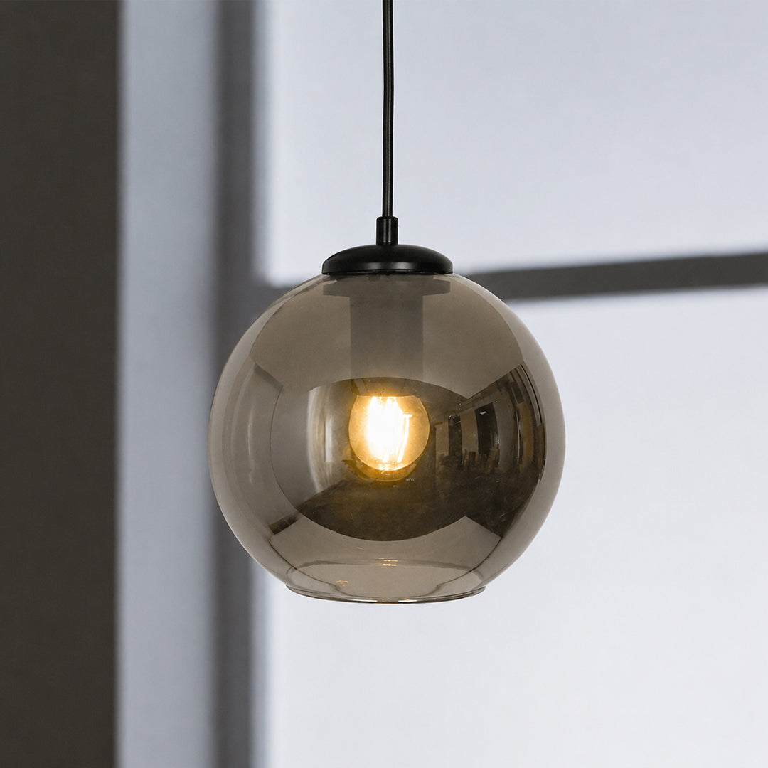 Smoked glass pendant light glowing softly with black fittings for stylish modern interiors.