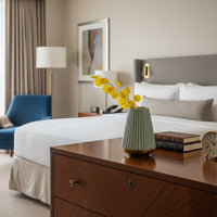 Tabletop decor vase styled on a wooden bedside table with yellow dried stems creating a calm and elegant bedroom interior setting.