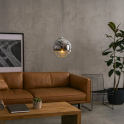 A smoked glass globe pendant light glowing warmly above a modern living room with leather sofa creating soft ambient lighting for contemporary home decor.