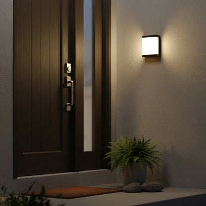 Outdoor wall light in black metal mounted beside entrance door casting warm ambient glow and enhancing modern exterior home lighting.