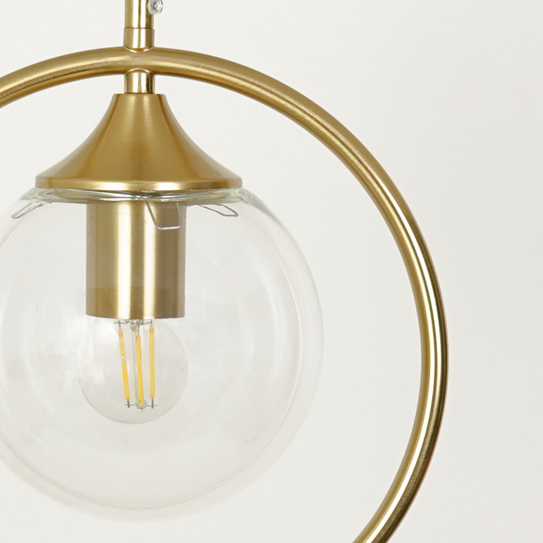 Closeup of gold ring pendant light with clear glass shade highlighting elegant brass details.