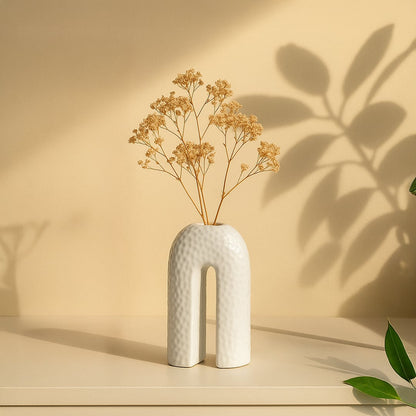 White ceramic arch-shaped vase with textured surface placed on beige background for modern artistic home decor.
