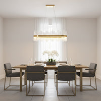 Gold metal chandelier with clear glass rods glowing warmly above a modern dining table creating an elegant bright and luxurious interior atmosphere.