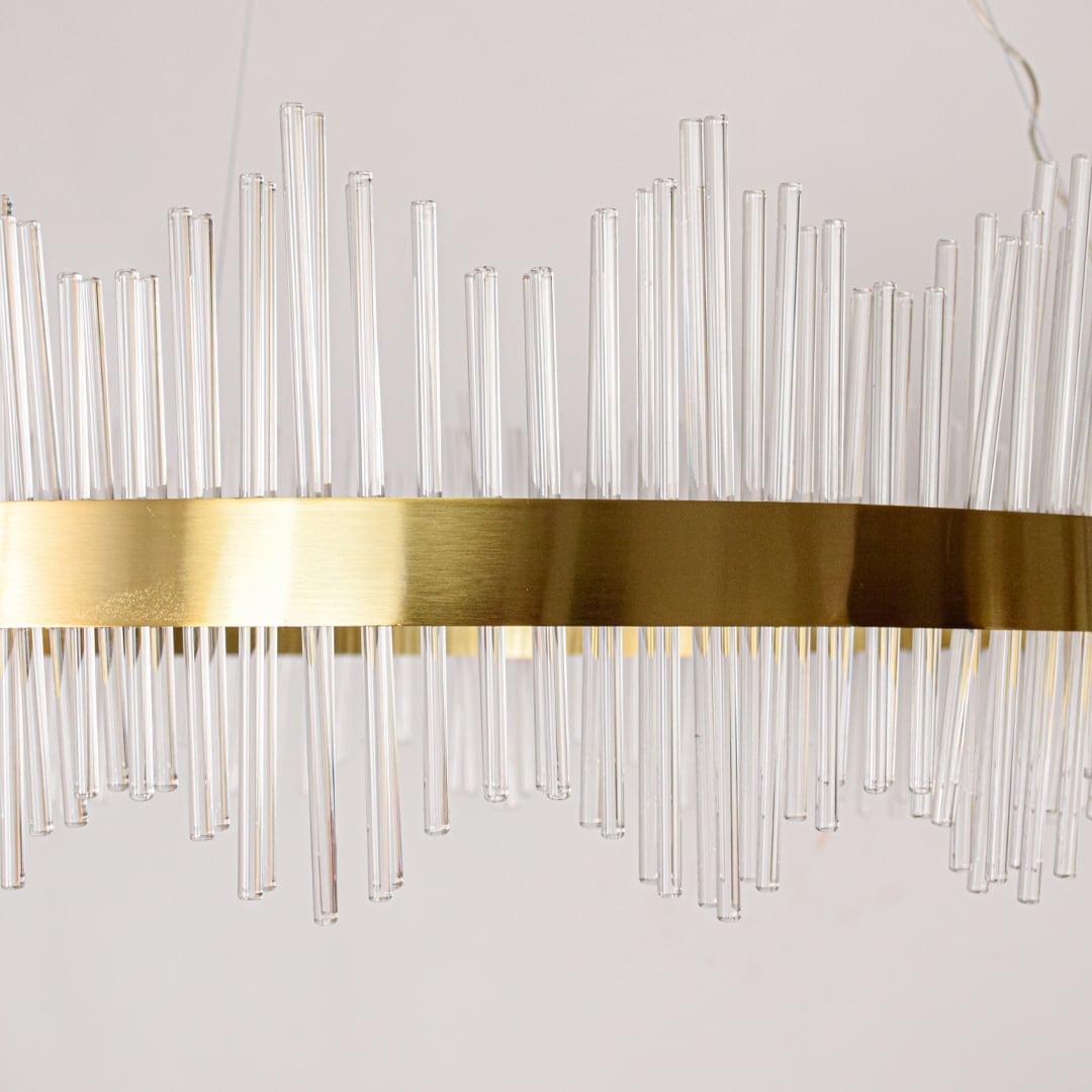 Closeup of gold metal chandelier band with clear glass rods showing refined craftsmanship and premium luxury lighting detail.